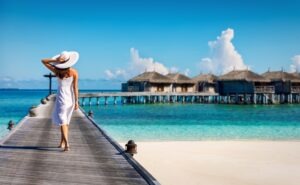 Woman in white walking over a wooden jetty in the Maldives