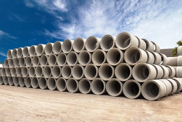Stack of concrete drainage pipes for wells and water discharges with blue sky