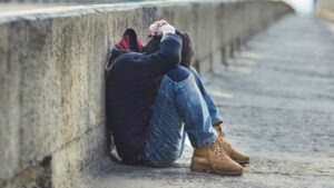 young homeless boy sleeping on the bridge, poverty, city, street