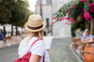 Woman traveler with city map is searching italian authentic street restaurant. Concept of travel, summer vacation