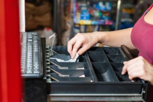 hand of an enterprising latina woman in her business opening the cash register. girl in front of cash register taking out money after making a sale. c