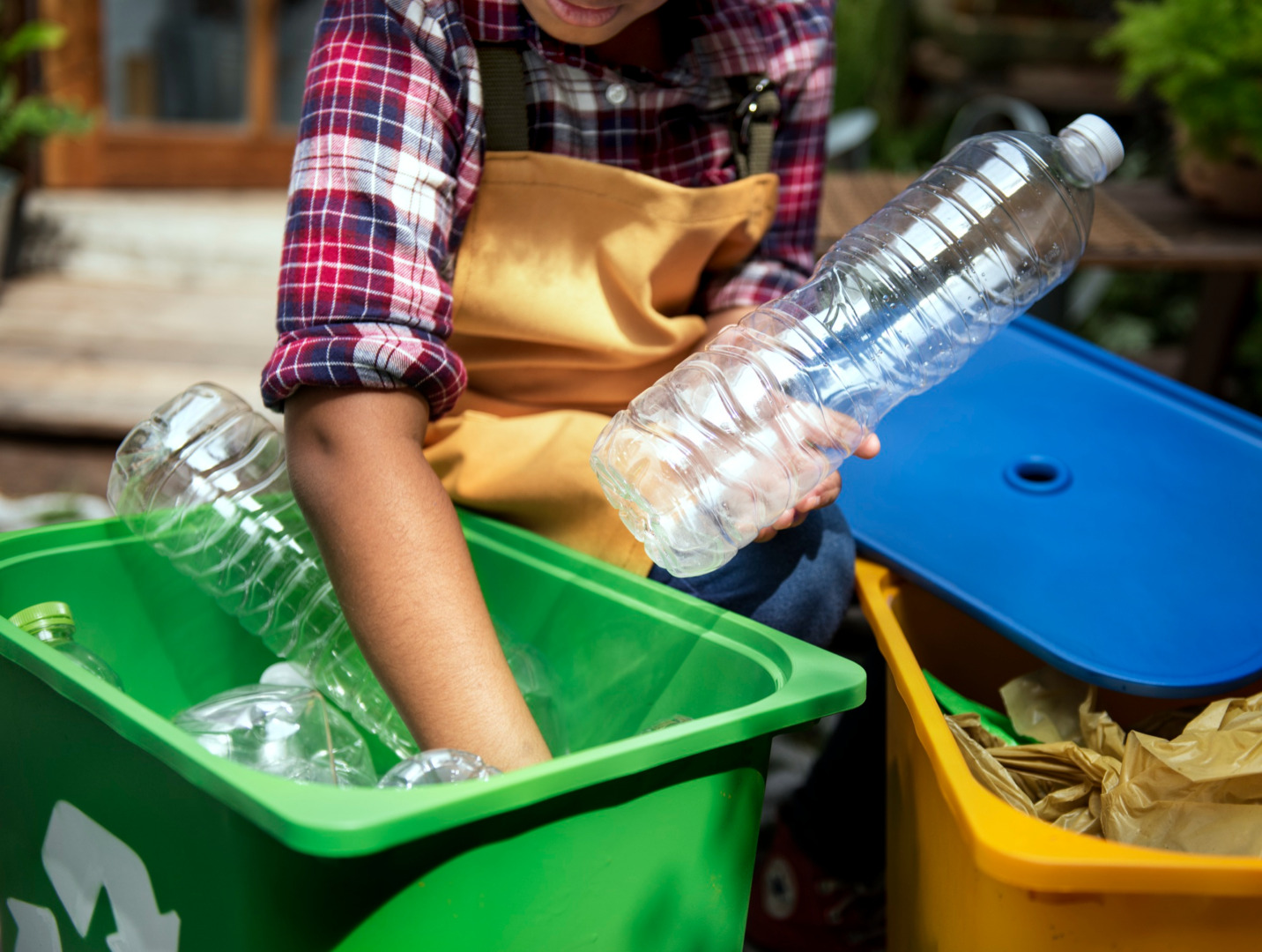 o persoana scoate sticle din plastic dintr-un tomberon