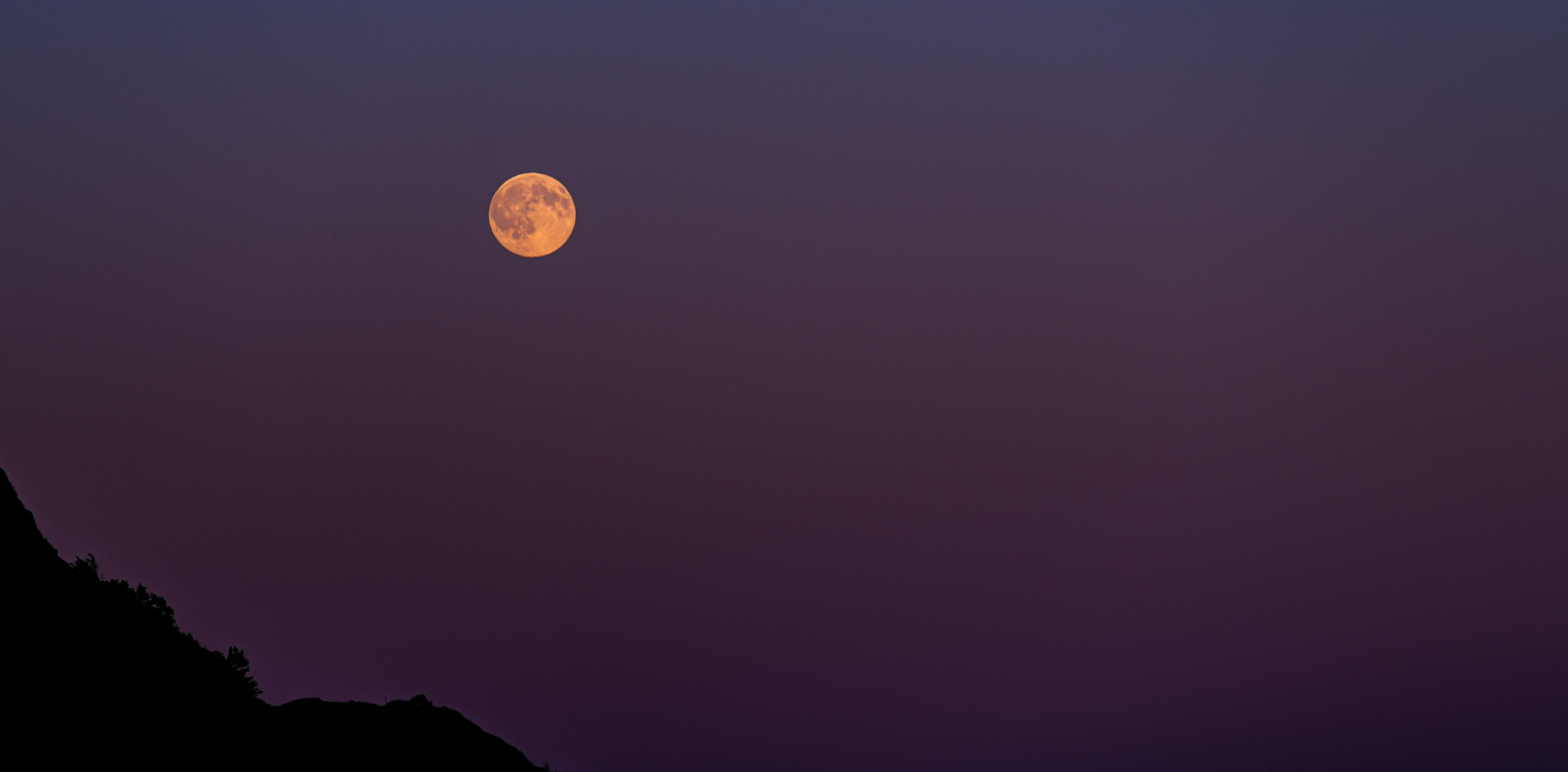 Luna în culori portocalii într-o noapte călduroasă de vară