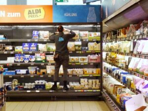 un angajat aldi aranjeaza produse pe un raft
