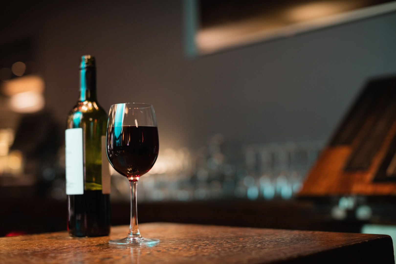 o sticla si un pahar de vin pe o masa